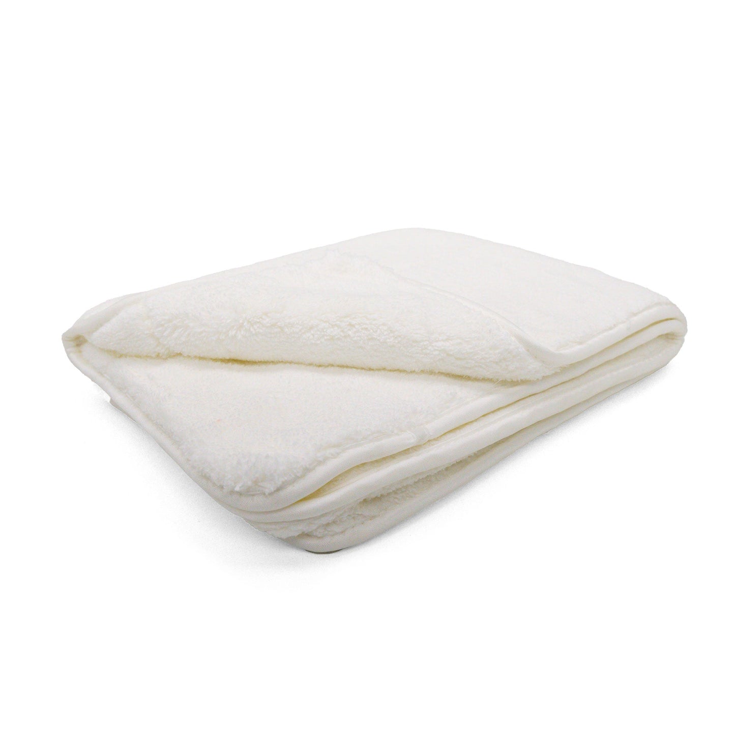 Photograph of a neatly folded cream plush blanket showcasing its soft texture and subtle shadows on a white background