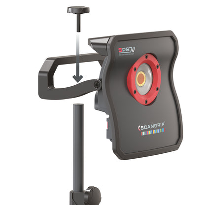 A dark gray ScanGrip SPS7 industrial work light featuring a red ring around its central light element, a colorful striped ScanGrip logo, and an arrow indicating attachment to a mounting pole