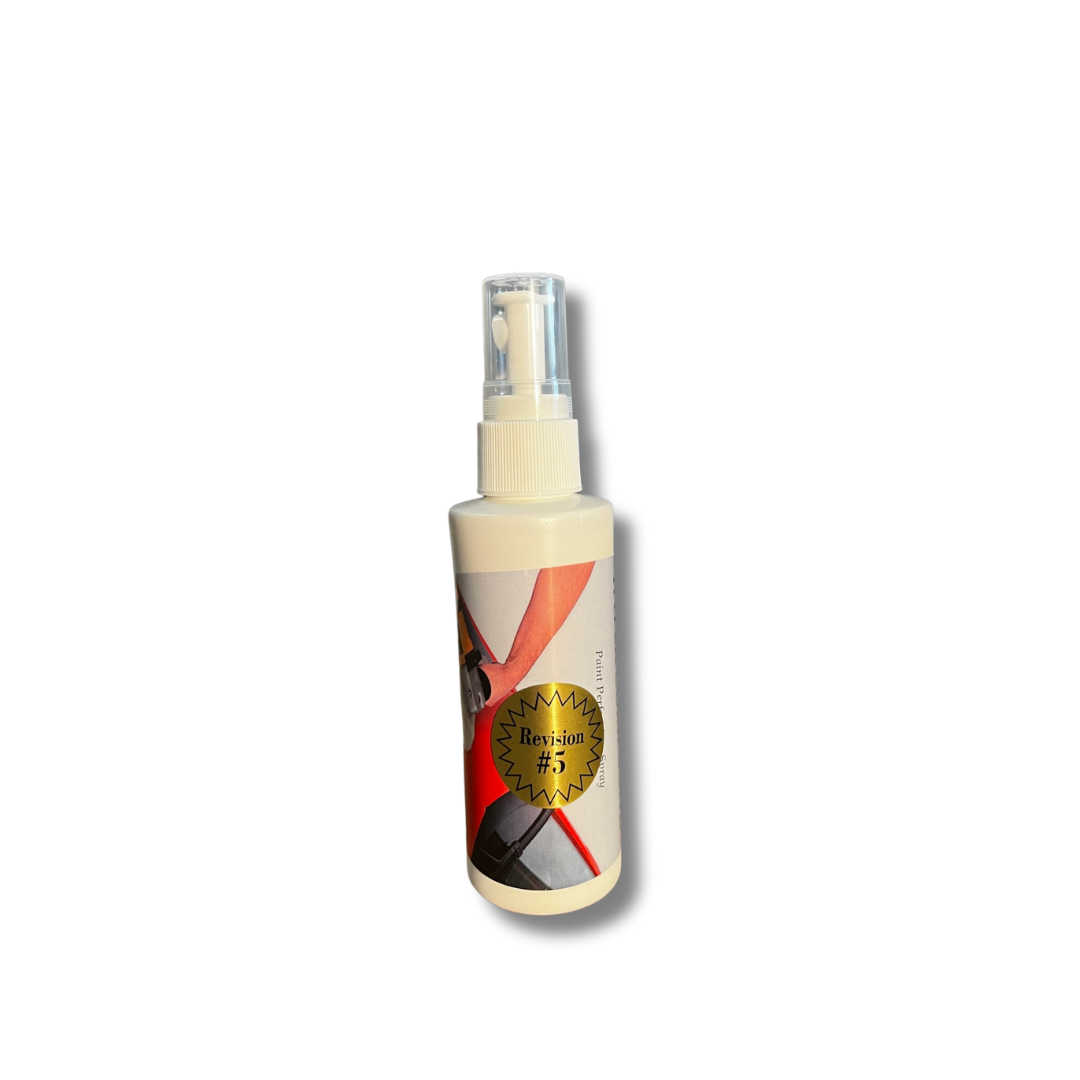 White spray bottle with a clear cap featuring an abstract label with red and black geometric shapes and a prominent gold seal marked Revision #5