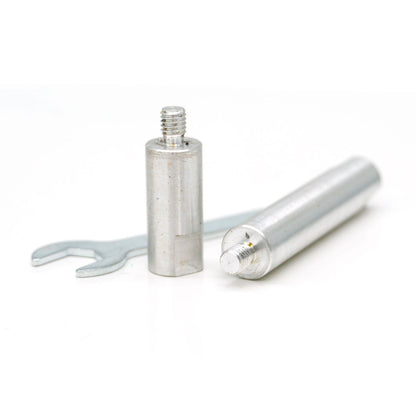 Photograph of a silver cylindrical threaded spacer standing upright next to another similar spacer lying horizontally, with a small silver open-ended wrench positioned behind them on a clean white studio background