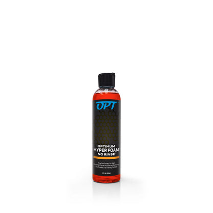 Product Photography of a clear bottle of Optimum Hyper Foam No Rinse car wash containing bright orange liquid, a black label with a blue OPT logo and subtle honeycomb pattern, topped with a black ribbed flip-top cap