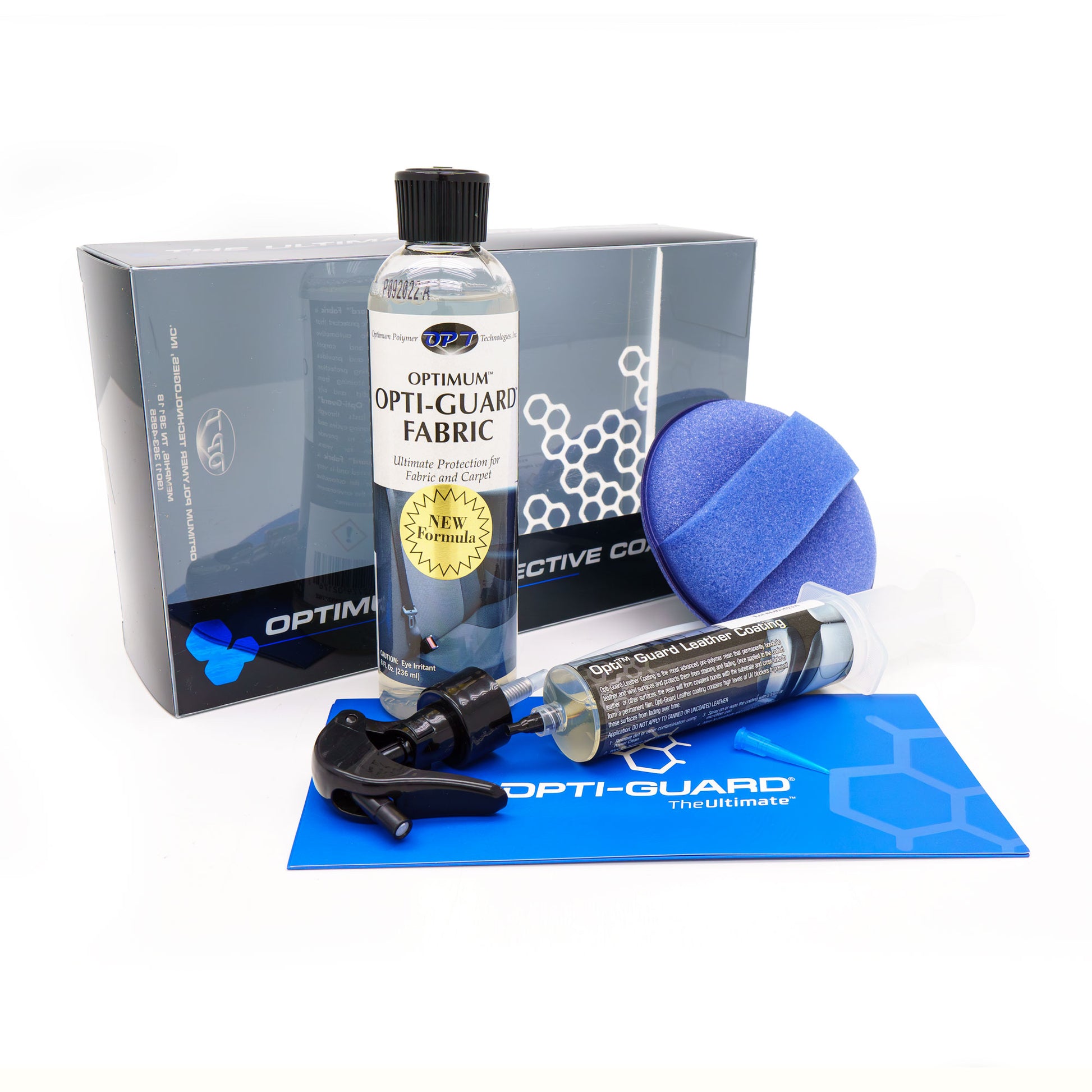 Product photography by Optimum Polymer Technologies of an Opti-Guard detailing kit on a white background, featuring a bottle of New Formula fabric protector, a blue sponge applicator, and a leather coating syringe next to a blue hexagonal mat