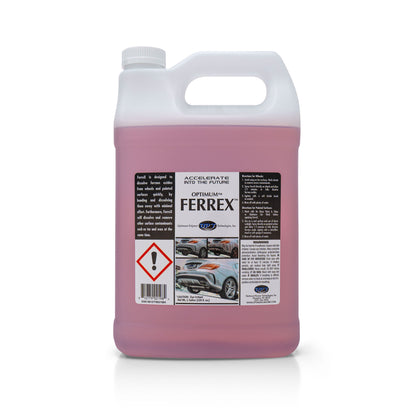 Product photography of a translucent white gallon jug of Optimum FerreX car detailing product containing bright pink liquid with a black and white label featuring usage instructions, images of a silver car's wheels and rear bumper, and a red hazard warning symbol