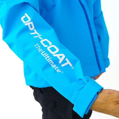 A person in a bright blue OPTI-COAT TheUltimate jacket featuring white text branding on the sleeve, with a rolled-up cuff and black pants, against a simple white background