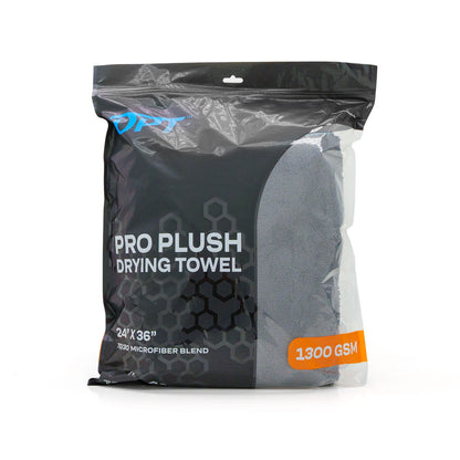 OPT Pro Plush Drying Towel in its dark gray plastic packaging featuring a blue OPT logo, bold "PRO PLUSH DRYING TOWEL" text, "24" X 36"" dimensions, "70/30 MICROFIBER BLEND", and a prominent orange "1300 GSM" sticker, set against a clean white studio background