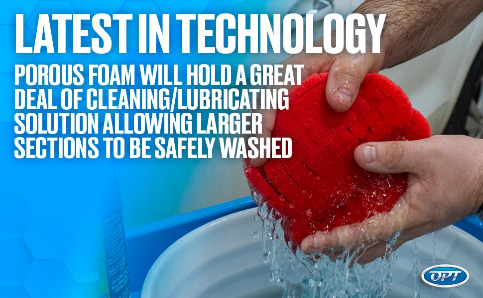 Hands squeeze a vibrant red porous foam pad over a white bucket, releasing clear water, with overlay text "LATEST IN TECHNOLOGY POROUS FOAM WILL HOLD A GREAT DEAL OF CLEANING/LUBRICATING SOLUTION ALLOWING LARGER SECTIONS TO BE SAFELY WASHED" and a blue OPT logo