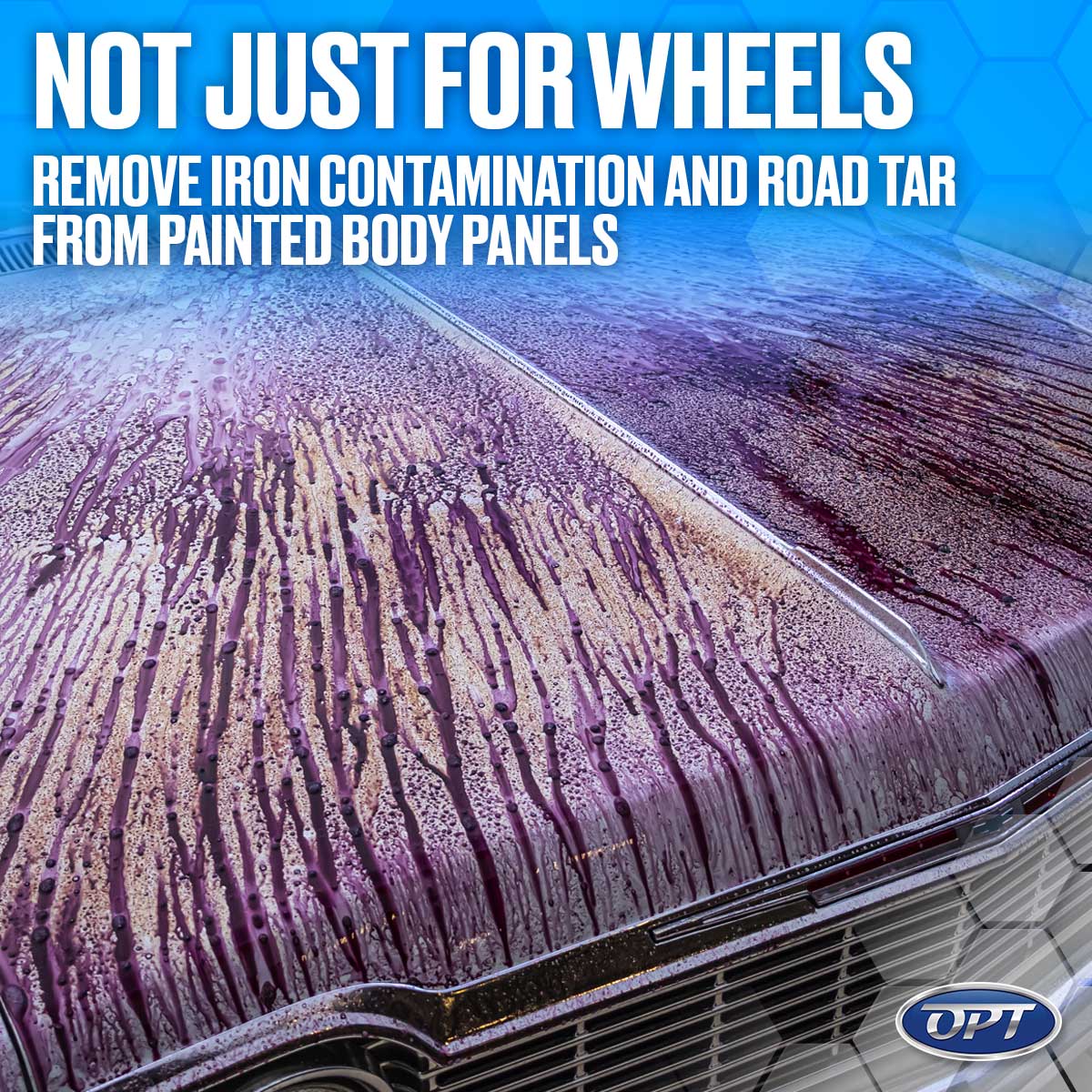 A classic car hood actively undergoing chemical decontamination with a purple iron remover creating white foamy streaks over its metallic paint and chrome grille