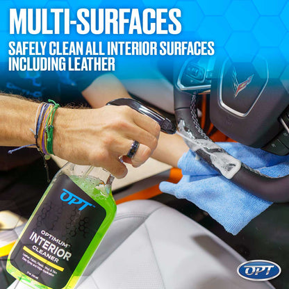 A person's hand, adorned with colorful bracelets, sprays white foam from a green OPT Optimum Interior Cleaner bottle onto a black leather Corvette steering wheel, with a blue microfiber towel ready to clean and white leather seats in the background, promoting safe multi-surface cleaning for car interiors including leather