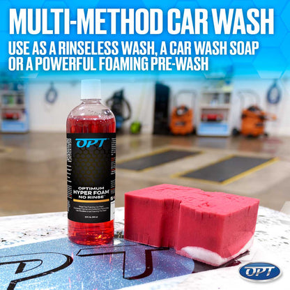 A transparent bottle of OPT Optimum Hyper Foam No Rinse car wash containing bright red liquid with a black and blue label is displayed next to a bright pink car wash sponge showing white residue on a sparkling blue surface in a car wash bay, highlighted by the text "MULTI-METHOD CAR WASH USE AS A RINSELESS WASH, A CAR WASH SOAP OR A POWERFUL FOAMING PRE-WASH"