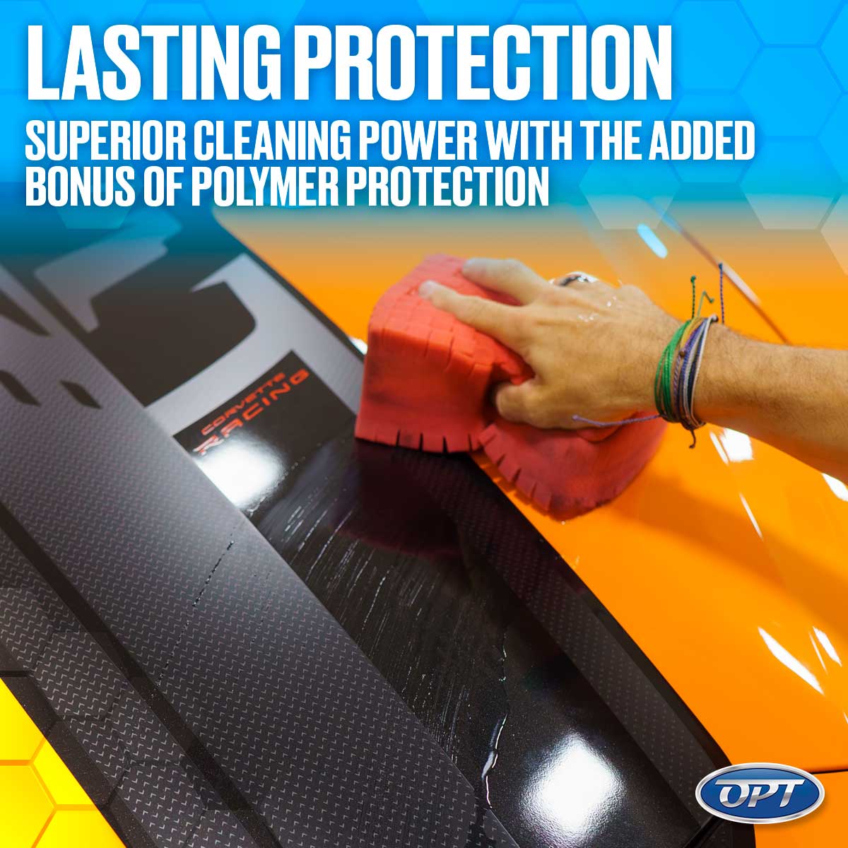 A hand with colorful bracelets applies a red cleaning sponge to a glossy orange and textured black Corvette surface showing the Corvette Racing logo and wet product streaks