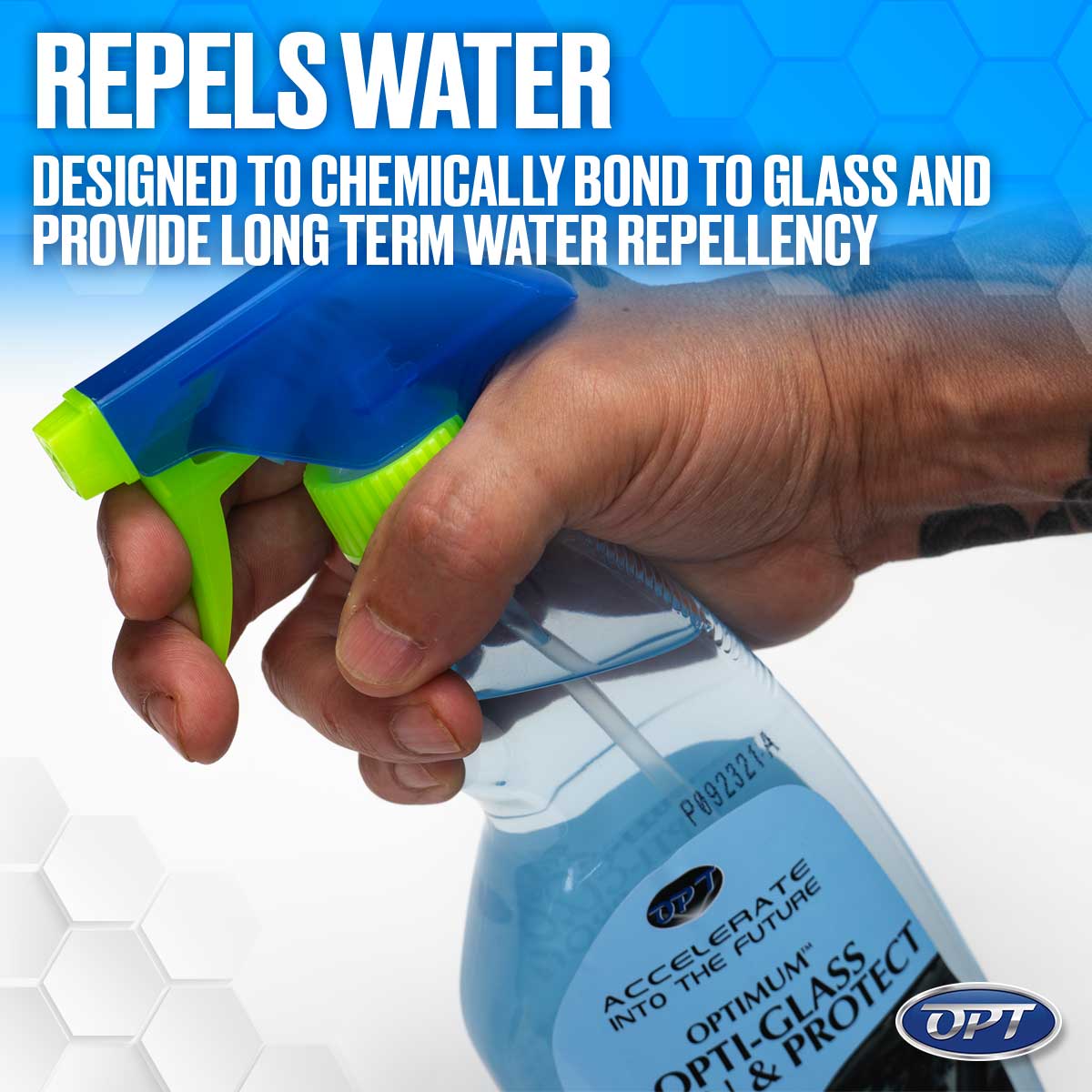 Product photo of a hand with a subtle wrist tattoo holding an OPT Optimum Opti-Glass & Protect spray bottle featuring a vibrant blue and neon green nozzle, filled with a light blue liquid, set against a subtle hexagonal background with prominent text stating REPELS WATER