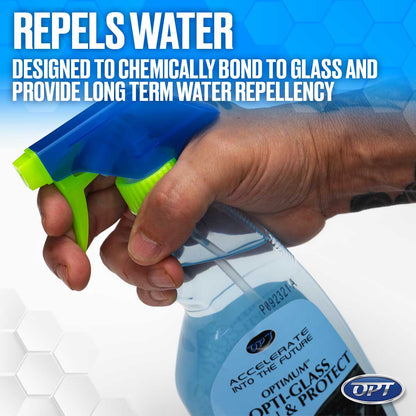 Product photo of a hand with a subtle wrist tattoo holding an OPT Optimum Opti-Glass & Protect spray bottle featuring a vibrant blue and neon green nozzle, filled with a light blue liquid, set against a subtle hexagonal background with prominent text stating REPELS WATER