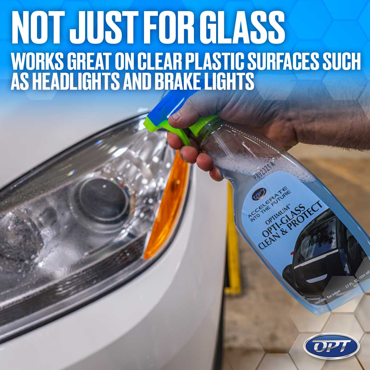 A hand sprays Optimum Opti-Glass Clean & Protect from a blue and lime green bottle onto a white car's clear headlight with orange turn signal, highlighting its use on clear plastic surfaces