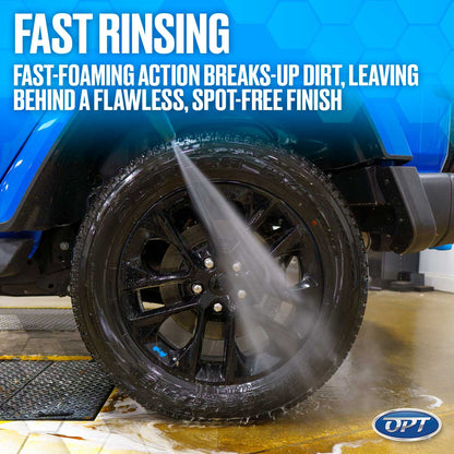 Digital photograph of a blue car's black wheel and tire being rinsed by a high-pressure water jet in a car wash bay with water and suds on the floor and marketing text "FAST RINSING" above