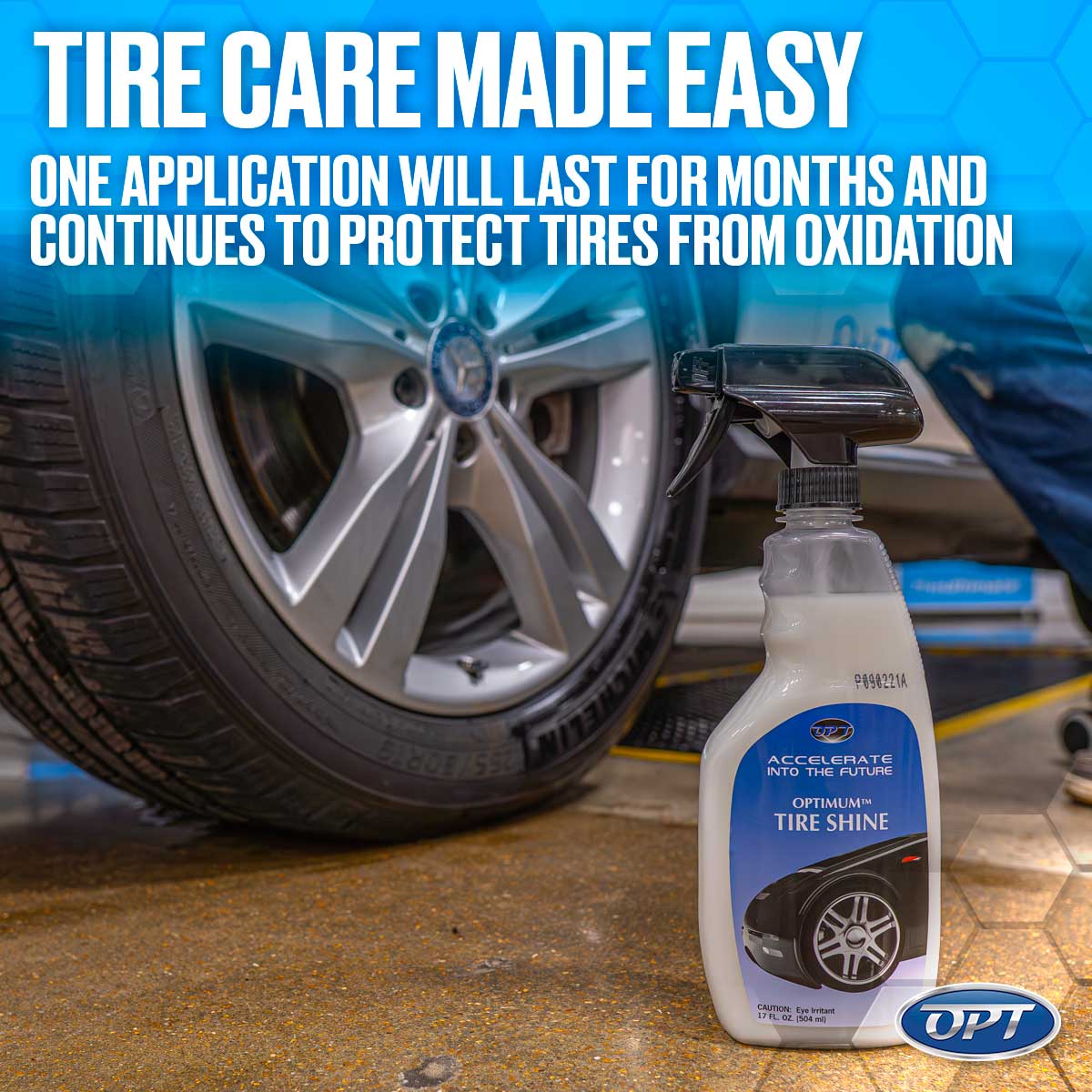 Commercial photograph featuring a white Optimum Tire Shine spray bottle on a concrete garage floor, positioned beside a gleaming silver Mercedes-Benz wheel and a dark Michelin tire, with a prominent blue and white overlay stating "TIRE CARE MADE EASY"