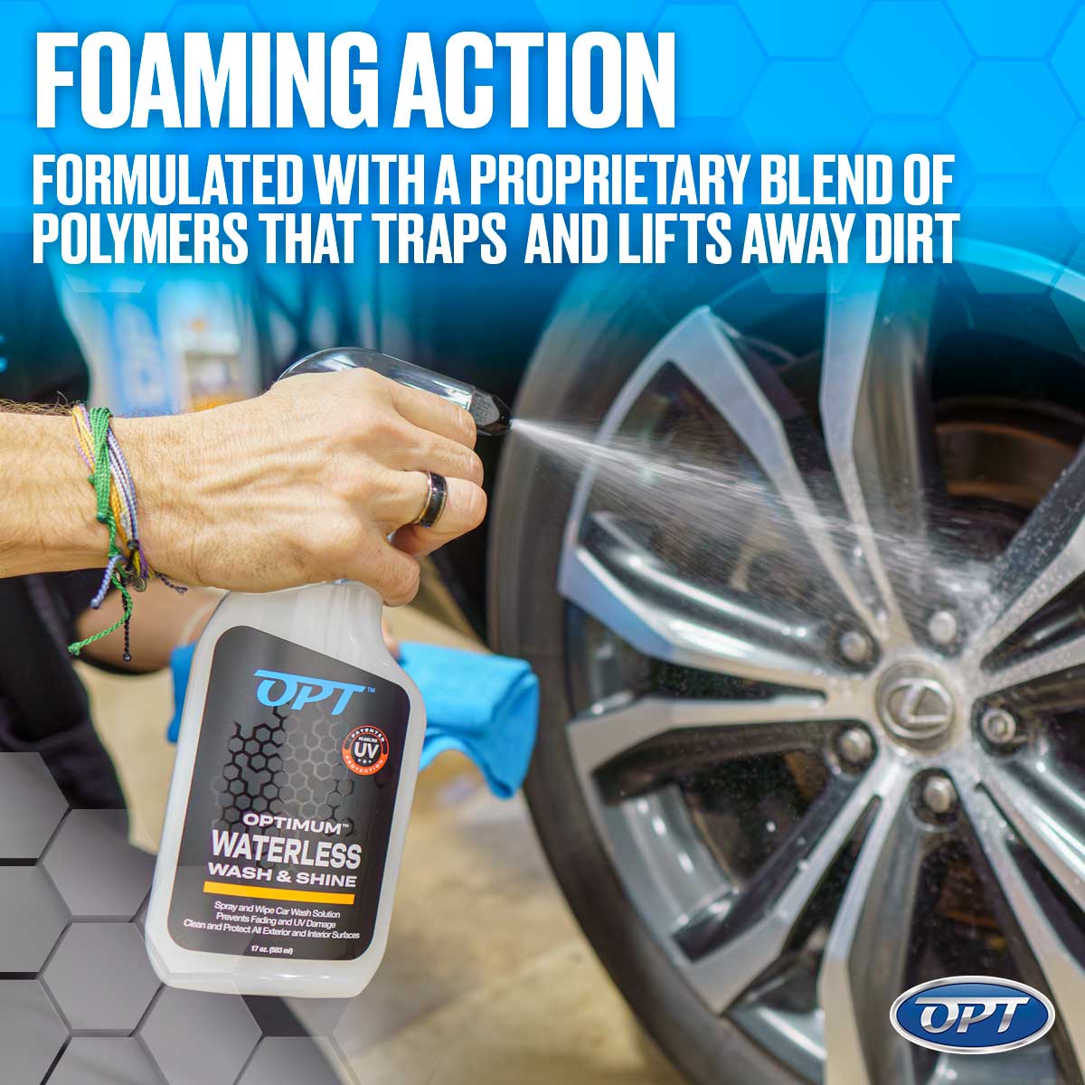 Photograph of a hand spraying OPT Optimum Waterless Wash & Shine from a white bottle onto a shiny Lexus car wheel, featuring colorful bracelets, a black ring, a blue microfiber towel, and a Foaming Action text overlay