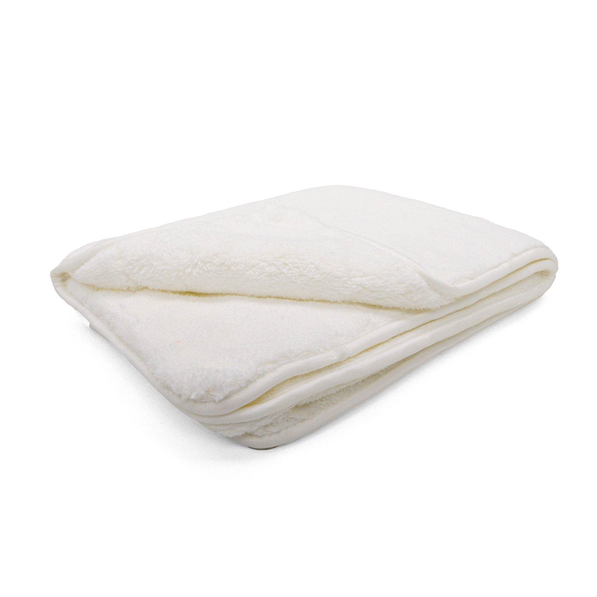 A soft cream-white plush blanket is meticulously folded, showcasing its fluffy texture against a clean white backdrop