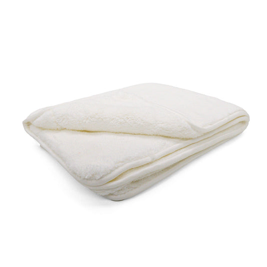 Photograph of a neatly folded cream plush blanket showcasing its soft texture and subtle shadows on a white background