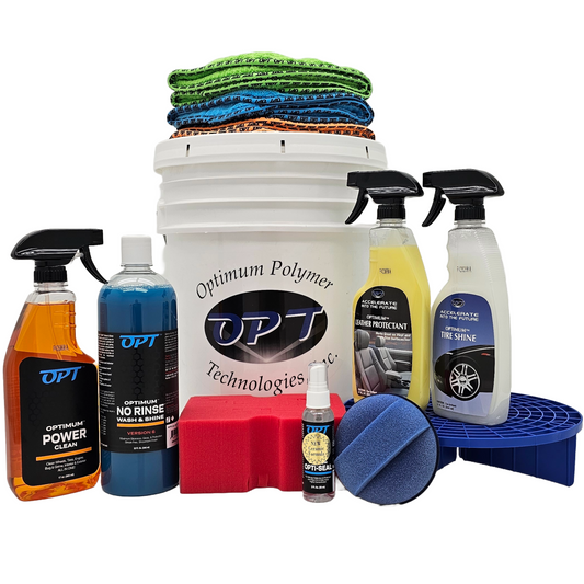 Optimum Polymer Technologies car detailing kit featuring a white bucket topped with stacked green, blue, and orange microfiber towels, an array of colorful cleaning liquid bottles including Power Clean, No Rinse Wash & Shine, Leather Protectant, and Tire Shine, a red wash sponge, a small Opti-Seal spray, and a blue grit guard with a matching applicator pad