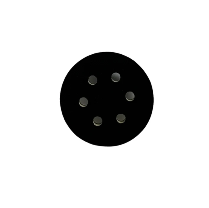 Photograph of a black circular pad with six light gray circular holes on a white background
